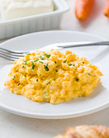 fresh scrambled eggs on white plate on breakfast tableの写真素材