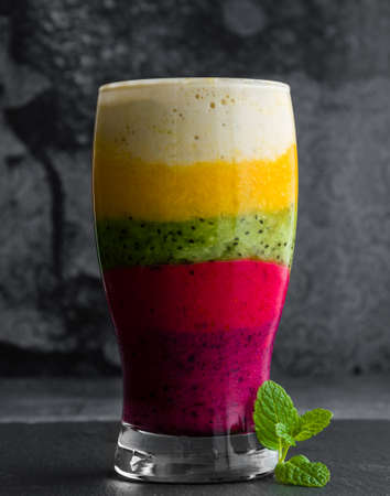 colorful smoothie made of different fruits layered in a glassの写真素材