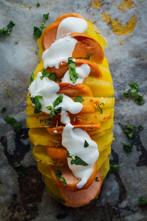 Baked hasselback potatoes with sausage and creamの写真素材