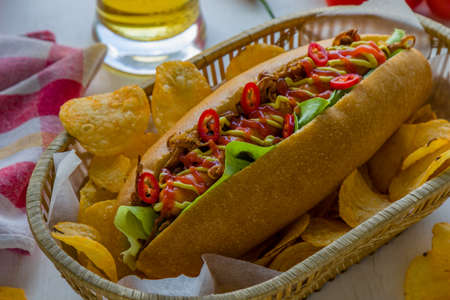 hot dog with lettuce onion mustard ketchup and potato chipsの写真素材
