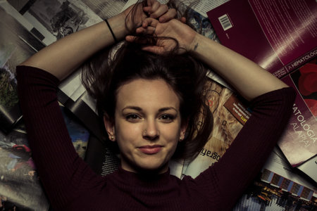 Portrait of young woman with books lying on floor