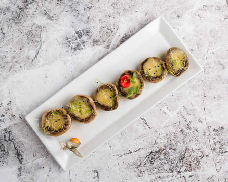 grilled mushroom stuffed with cheese on white plateの写真素材