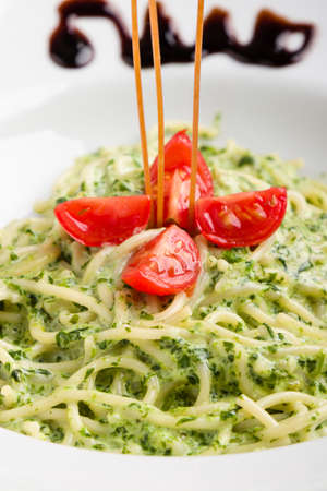 tasty spinach with spaghetti pasta on white plateの写真素材