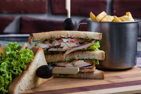 tasty chicken club sandwich with fries on wooden tableの写真素材