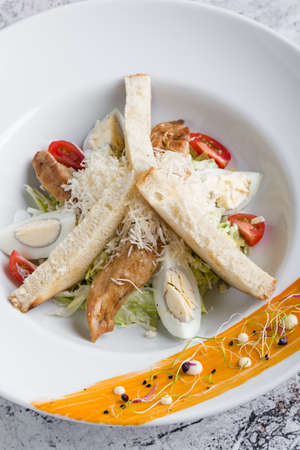 fresh tasty caesar salad appetizer in white plateの写真素材