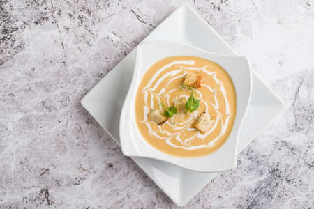 fresh vegetable cream soup with bread crums in white plateの写真素材