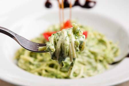 tasty spinach with spaghetti pasta on white plateの写真素材