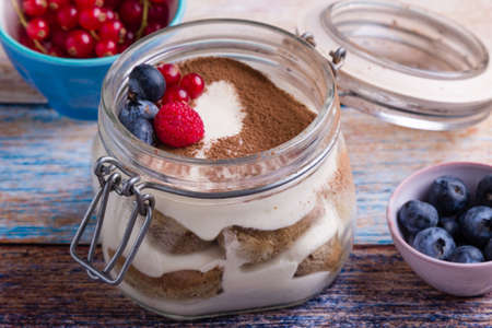 tasty tiramisu dessert in glass jar on color tableの写真素材
