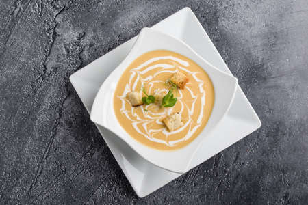 fresh vegetable cream soup with bread crums in white plateの写真素材