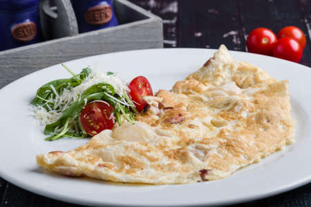 filled omelette with cheese and tomato on white plateの写真素材