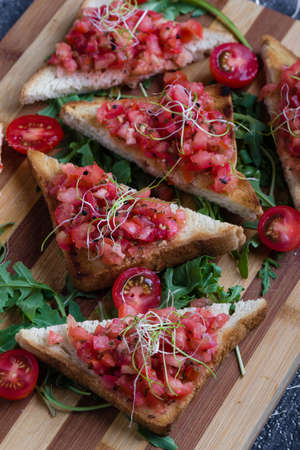 bruschetta with tomato basil and rucola on wooden boardの写真素材