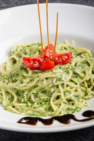 tasty spinach with spaghetti pasta on white plateの写真素材