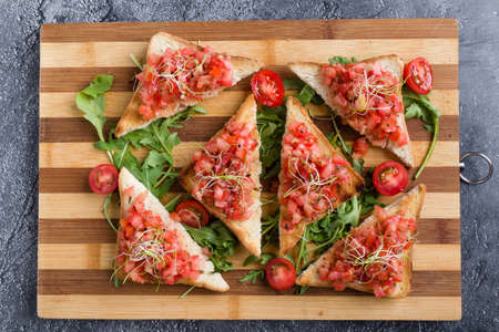 bruschetta with tomato basil and rucola on wooden boardの写真素材