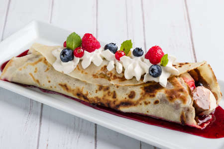 european pancakes, sweet crepe with topping on white long plateの写真素材