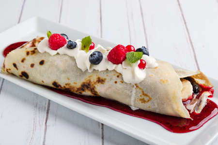 european pancakes, sweet crepe with topping on white long plateの写真素材