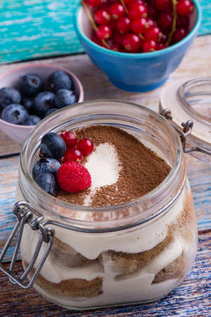 tasty tiramisu dessert in glass jar on color tableの写真素材