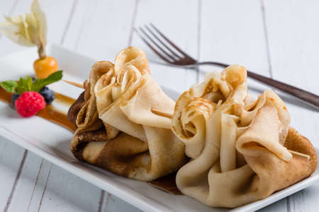 european pancakes, sweet crepe with topping on white long plateの写真素材