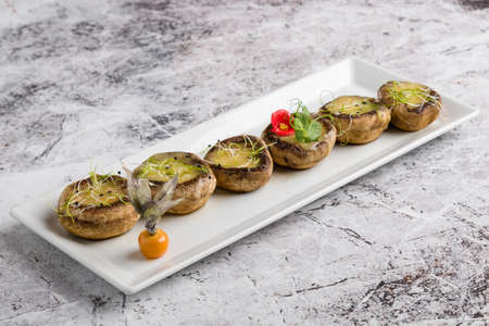 grilled mushroom stuffed with cheese on white plateの写真素材