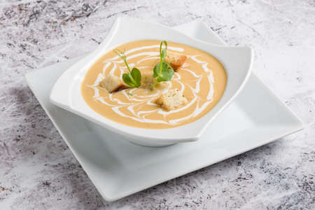 fresh vegetable cream soup with bread crums in white plateの写真素材