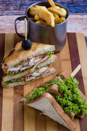 tasty chicken club sandwich with fries on wooden tableの写真素材