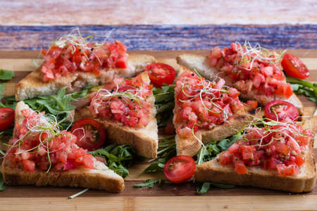 bruschetta with tomato basil and rucola on wooden boardの写真素材
