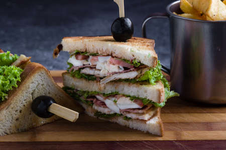 tasty chicken club sandwich with fries on wooden tableの写真素材