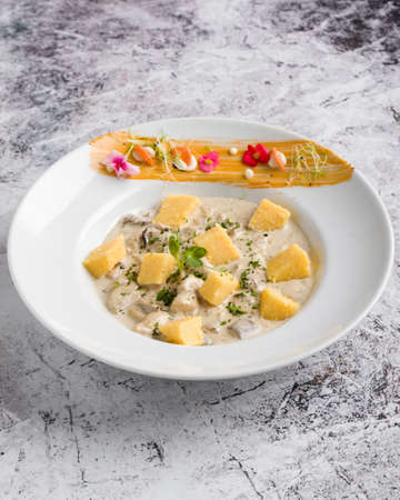 chicken with mushrooms sauce and polenta cubes in white tableの写真素材