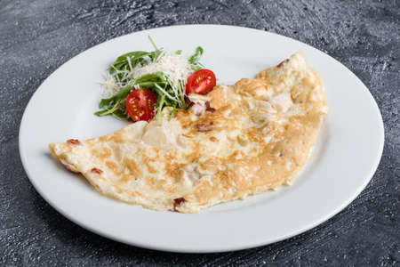filled omelette with cheese and tomato on white plateの写真素材
