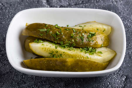 salted sour pickles with herbs in white bowlの写真素材