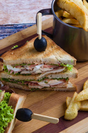 tasty chicken club sandwich with fries on wooden tableの写真素材