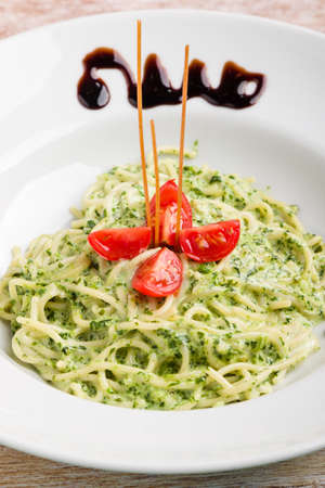 tasty spinach with spaghetti pasta on white plateの写真素材