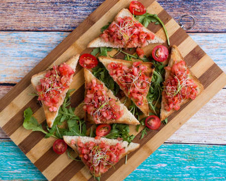 bruschetta with tomato basil and rucola on wooden boardの写真素材