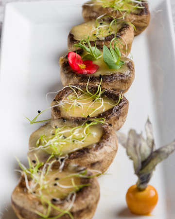 grilled mushroom stuffed with cheese on white plateの写真素材