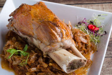 bavarian pork knuckle with cabbage on white plateの写真素材