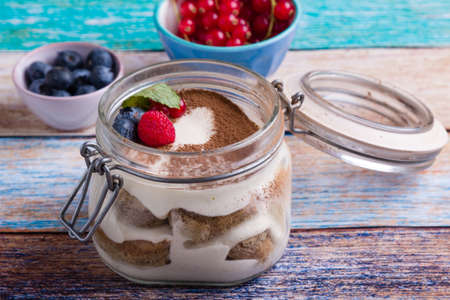 tasty tiramisu dessert in glass jar on color tableの写真素材