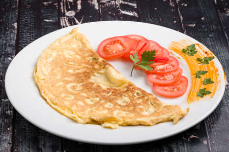 filled omelette with cheese and tomato on white plateの写真素材