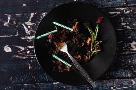 black plate with messy leftover from cake with candlesの写真素材