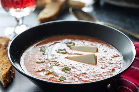 Rustic tomato soup with white cheese in black bowlの写真素材