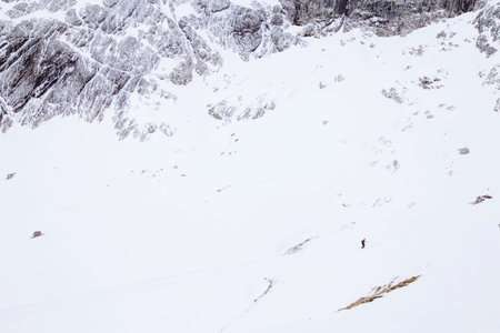 Woman moving up on snowy slope to top of mountainの写真素材