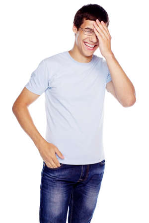 Laughing young man in glasses and blue shirt with hand on his face isolated on white backgroundの写真素材