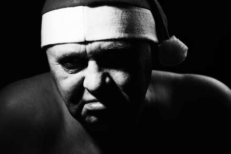 Close up black and white portrait of ominous mature man in Santa Claus hatの写真素材