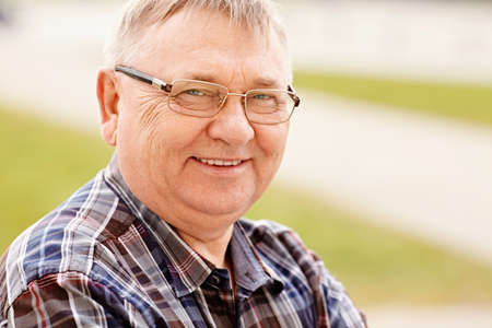 Close up outdoors portrait of smiling middle aged man in glasses and cheered shirt