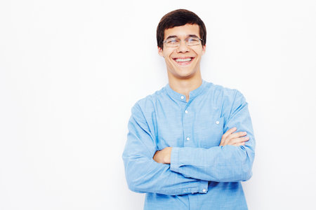 Young hispanic man wearing jeans and glasses standing with crossed arms and smiling against white wallの写真素材