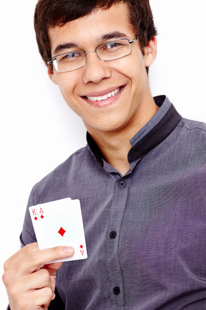 Close up portrait of young hispanic man wearing grey shirt and glasses holding Ace King in his hand...