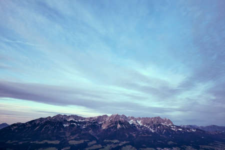Mountain landscape with snow capped tops of alpine sierra against moody skyの写真素材