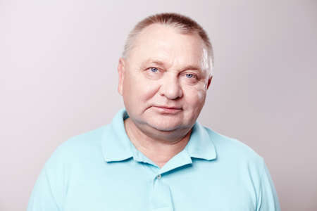 Portrait of aged man wearing blue shirt against white background - retirement concept