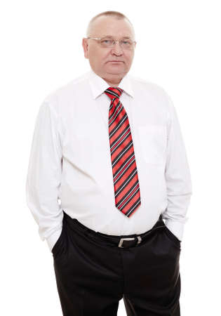 Serious middle aged businessman wearing glasses, red and black striped tie with white shirt and black trousers standing with hands in pockets isolated on white background - human resources conceptの写真素材