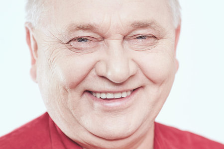 Close up portrait of laughing aged man wearing red shirt against white background - wellbeing conceptの写真素材