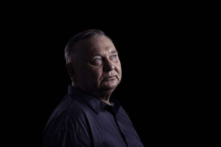 Classic portrait of aged man wearing shirt against black background - retirement concept, copy spaceの写真素材