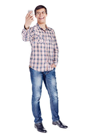 Full body portrait of cheerful young man having video call on mobile phone wearing metal frame glasses, checkered shirt, blue jeans and black shoes isolated on white backgroundの写真素材